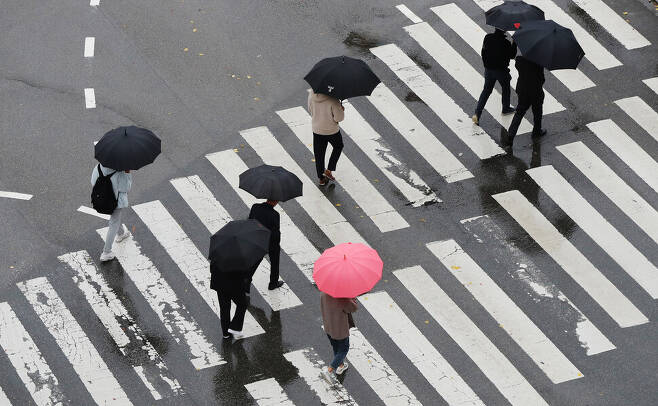 겨울비가 온종일 쏟아진 지난달 30일 오전 광주 북구청 앞 도로에서 우산 쓴 시민들이 계단을 오르듯 횡단보도를 건너고 있다. 연합뉴스