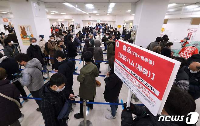 1일 일본 도쿄 한 백화점에 마스크를 착용한 사람들이 새해 기념 행운가방을 사기 위해 줄 서 있다. 2022.01.01 © AFP=뉴스1