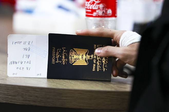 한 이라크 이민자가 여권을 손에 들고 벨라루스 공항에서 대기하고 있다./AP 연합뉴스