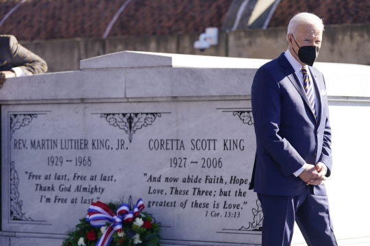 조 바이든 미국 대통령이 11일 흑인 인권 운동가 마틴 루서 킹 목사와 그의 아내 코레타 스콧 킹의 무덤에 헌화한 뒤 두 손을 모으고 걸어 나오고 있다.  AP 연합뉴스