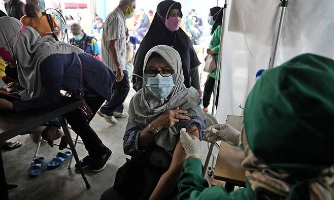 12일(현지시간) 인도네시아 자카르타 보건소에서 한 여성이 코로나19 백신 ‘부스터샷’, 추가 접종을 하고 있다. 자카르타=AP연합뉴스