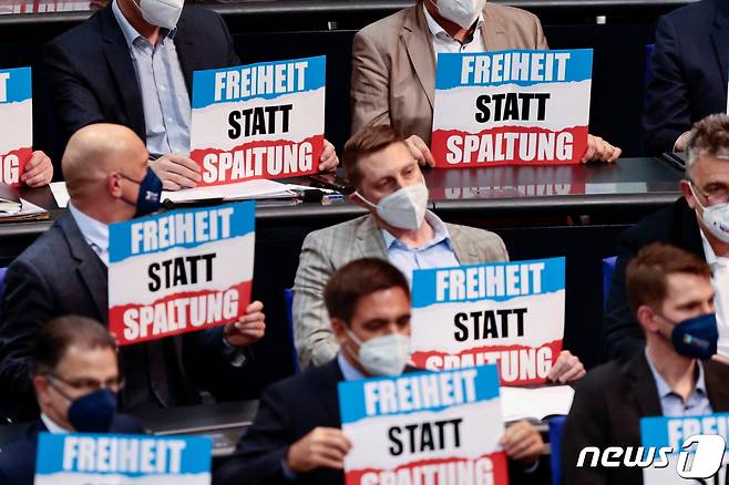 12일(현지시간) 극우 성향의 독일을 위한 대안(AfD) 의원들이 숄츠 총리의 첫 의회 질의응답이 진행되는 동안 '분열 대신 자유'라고 적힌 팻말을 들고 있다. © 로이터=뉴스1