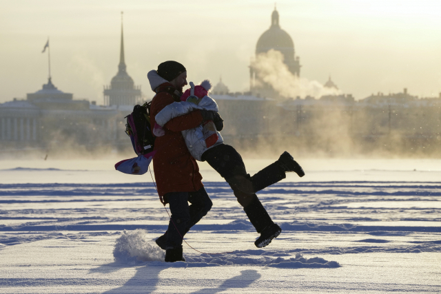 얼어붙은 상트페테르부르크 네바강 위에서 11일(현지시간) 한 남성이 딸과 놀아주고 있다. /AP연합뉴스