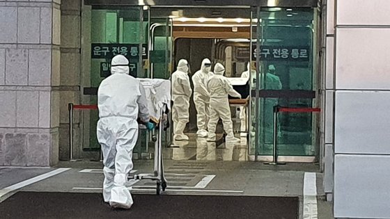 지난해 12월 경기도의 한 화장터에서 레벨D 방호복을 입은 직원들이 코로나19 사망자의 관을 옮기고 있다. [한국장례협회 제공]