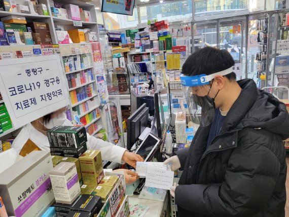 14일 오후 서울 중랑구 지역 전담약국에서 중랑구보건소 직원이 코로나19 경구용 치료제 ‘팍스로비드’를 전달받고 있다/사진=중랑구 제공
