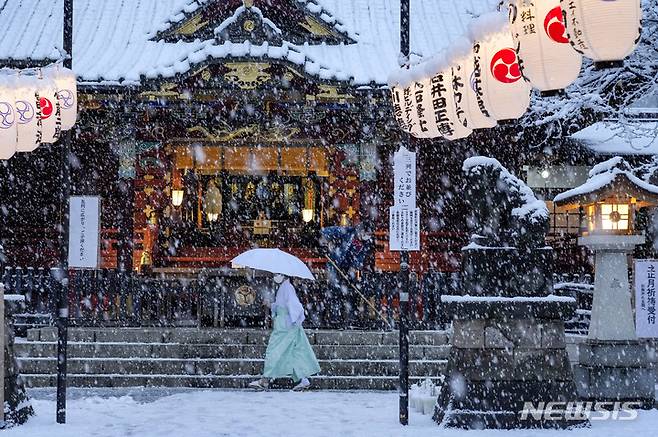 [도쿄(일본)=AP/뉴시스]지난 6일 일본 도쿄의 한 신사에 눈이 내리자 직원들이 마스크를 착용한 채 눈을 치우고 있다. 2022.01.15.