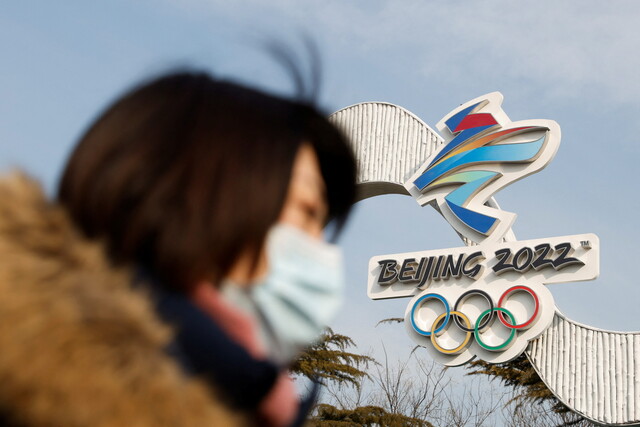 18일 중국 베이징 국가빙상경기장에 설치된 겨울올림픽 상징물 앞을 마스크를 쓴 시민이 지나고 있다. 베이징/로이터 연합뉴스