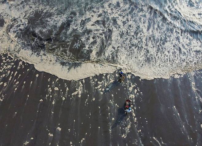 지난 19일(현지시각) 페루의 벤타니아 해변. 기름을 치우고 있다. /로이터 연합뉴스