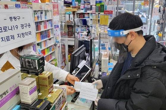 14일 서울 지역 전담약국에서 중랑구보건소 직원이 코로나19 먹는 치료제 '팍스로비드'를 받고 있다. 연합 뉴스.