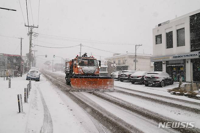 [아테네(그리스)=AP/뉴시스] 24일(현지시간) 그리스 아테네 북쪽 아기오스 스테파노스에 눈이 내리는 동안 제설 차량이 도로의 눈을 치우고 있다. 2022.01.25.