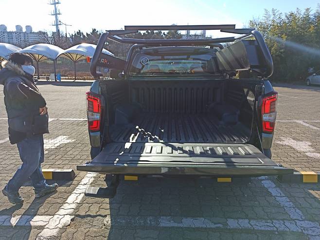 쌍용차 렉스턴 스포츠 칸 익스페디션 트림 후면. 지나가는 행인이 차량을 살펴보고 있다.