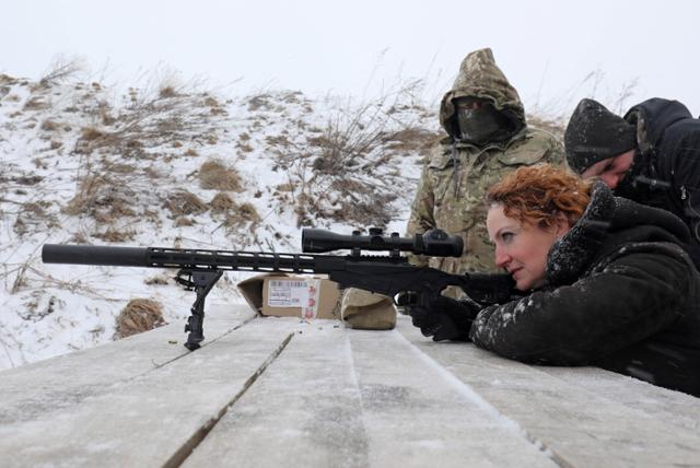 25일 우크라이나 리비프 외곽에서 필수 도시 산업 및 서비스 직원을 위한 군사 훈련 중 한 여성이 소총 사격 준비를 하고 있다. 리비프=로이터 연합뉴스