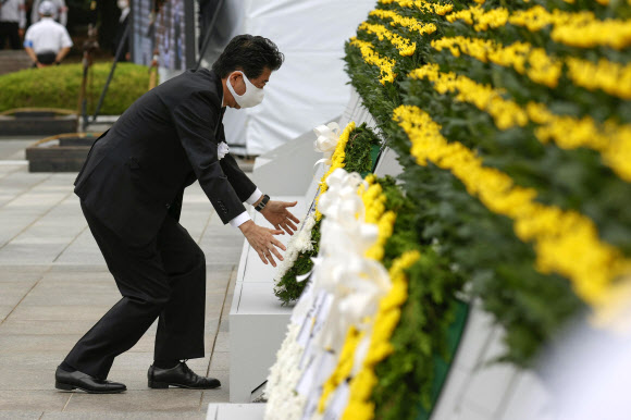히로시마 원폭 위령비에 헌화하는 아베 일본 총리 - 아베 신조 일본 총리가 6일 히로시마 평화기념공원에서 거행된 원폭 투하 75주년 행사에 참석해 희생자 위령비 앞에 헌화하고 있다.교도 통신 제공/로이터 연합뉴스