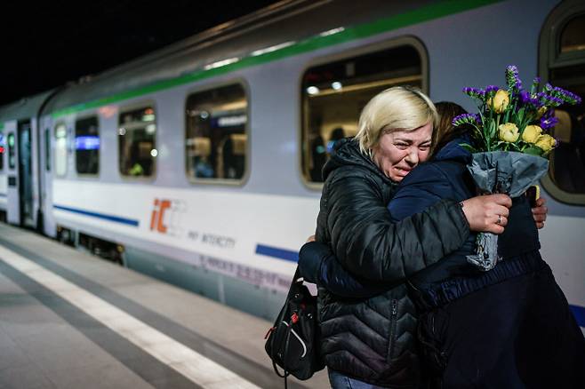 우크라이나 국기색 꽃을 든 한 시민이 2일 우크라이나 피란민들을 태운 열차에서 내린 승객을 끌어안고 있다. / EPA연합뉴스