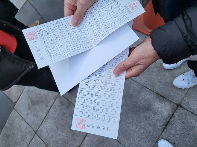 5일 오후 서울 은평구 신사1동 투표소 확진자 임시기표소에서 40대 유권자가 자신의 투표용지(맨밑장)를 담을 봉투(가운데) 속에서 '1번 이재명 더불어민주당 후보'에 기표된 투표용지(맨윗장)를 발견했다. 이 일로 기다리던 유권자 열댓명이 항의 끝에 투표를 포기하고 집으로 돌아갔다. 봉투를 들고온 보조원은 "나는 모른다"는 말만 반복했다. /독자제공