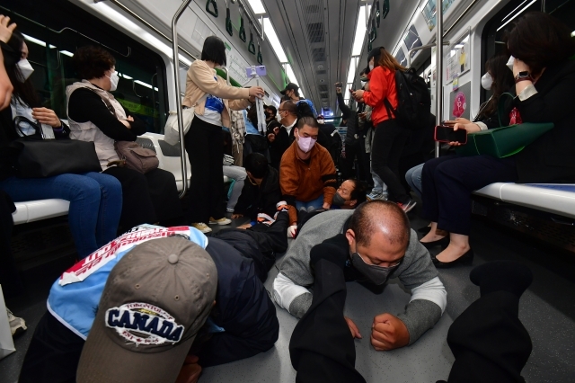 열차에 기어서 올라탄 전장연 회원들이 승객 사이를 기어서 지나가며 시위하고 있다.