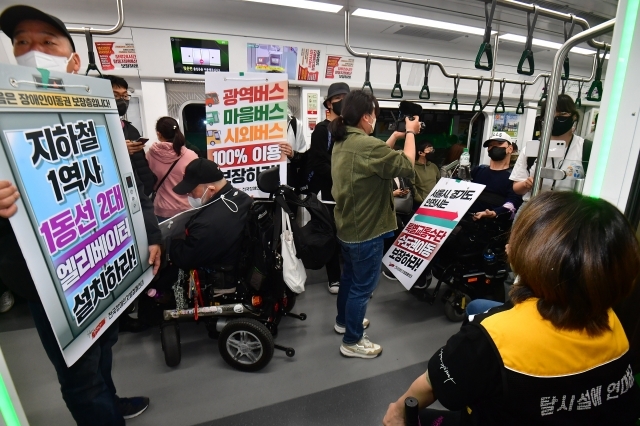 열차에 올라탄 전장연 회원들이 장애인 이동권 대책을 촉구하는 문구가 담긴 팻말을 들고 시위를 이어가고 있다.