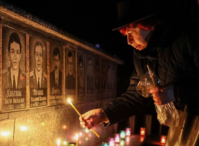 체르노빌 원전 폭발 참사 36주년 하루 앞둔 25일(현지시각) 우크라이나 슬라우티크에서 한 여성이 사고 수습 과정에서 희생된 소방관 등을 추모하는 촛불을 밝히고 있다. /연합뉴스