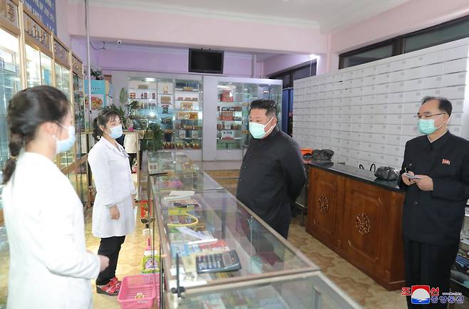 A photo released by the official North Korean Central News Agency (KCNA) shows North Korean leader Kim Jong-un (center) wearing a face mask while inspecting a pharmacy in Pyongyang, North Korea, Sunday. (Yonhap)　