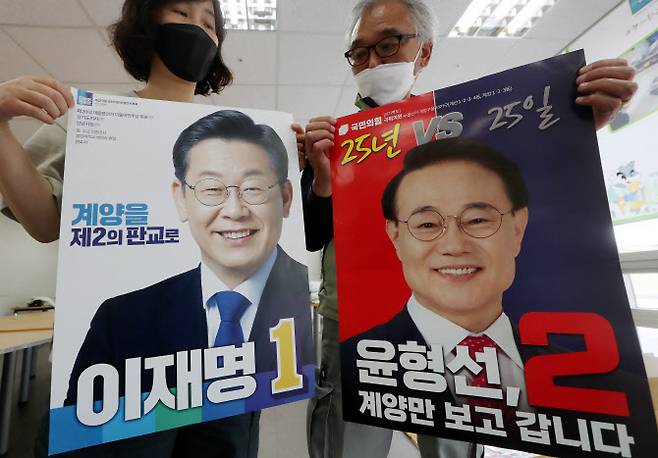 6·1 지방선거운동 개시일을 하루 앞둔 18일 오후 인천시 계양구 계양경기장 선거 벽보 분류 작업장에서 계양구 선거관리위원회 관계자들이 인천 계양을 보궐선거 더불어민주당 이재명 후보와 국민의힘 윤형선 후보의 선거 벽보를 공개하고 있다. (사진= 연합뉴스)