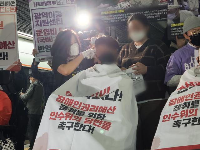 강희석 나야장애인권교육센터 활동가가 이달 3일 경복궁역에서 진행된 삭발식에서 삭발 결의자의 머리를 자르고 있다. 박지영 기자