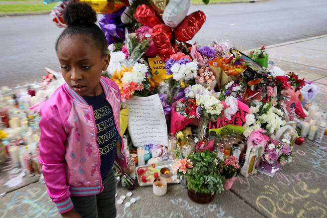 흑인을 겨냥한 총기난사가 일어난 미국 뉴욕주 버팔로의 슈퍼마켓 인근에 마련된 추모 현장에 18일(현지시간) 한 소녀가 서 있다.  로이터연합뉴스