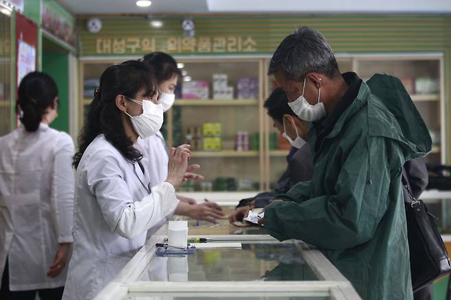 In this photo published by the Korea Central News Agency on Tuesday, a medical worker at a pharmacy is seen wearing two layers of face mask. (Yonhap)