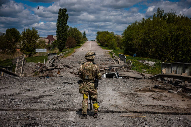우크라이나 병사가 16일(현지시간) 하르키우(하리코프) 북쪽 루스카 로조바 마을 인근의 파괴된 다리 앞에서 경계근무를 서고 있다. 연합뉴스