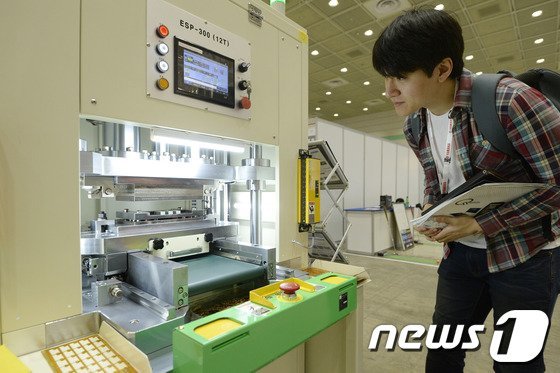 인쇄회로기판 생산기를 살펴보고 있는 관람객의 모습. © 뉴스1