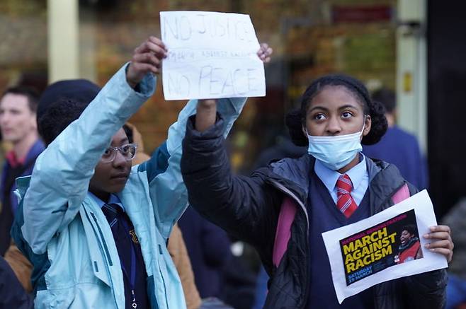 [런던=AP/뉴시스] 지난 3월18일 런던 스토크 뉴잉턴 경찰서 밖에서 경찰에 의해 알몸 수색을 당한 흑인 15세 여학생의 처우에 항의하기 위해 사람들이 모여든 가운데 같은 학교 아이들이 항의 포스터를 들고 있다. 2022.05.24. *재판매 및 DB 금지