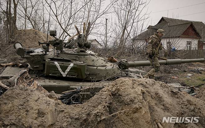 [안드리우카=AP/뉴시스] 5일(현지시간) 우크라이나 키이우 동부 안드리우카에서 우크라이나 군인이 버려진 러시아군의 전차에 올라가 살피고 있다. 2022.04.06.