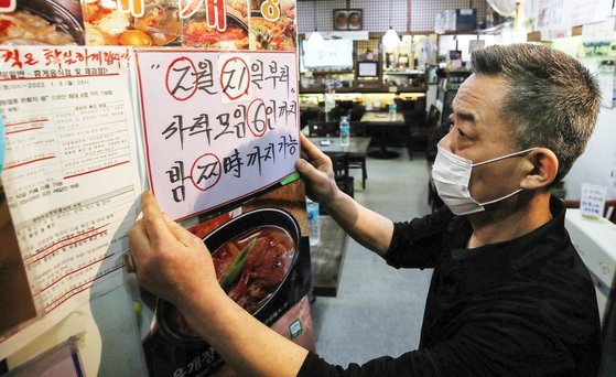 서울 광화문의 한 음식점에서 자영업자가 새 거리두기 조정안 문구가 적힌 안내문을 붙이고 있다.  뉴스1