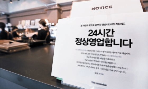 지난해 12월 경기도 용인의 한 카페에 영업 제한 조치를 거부하고 24시간 영업을 한다는 안내문이 붙어 있다. 뉴시스
