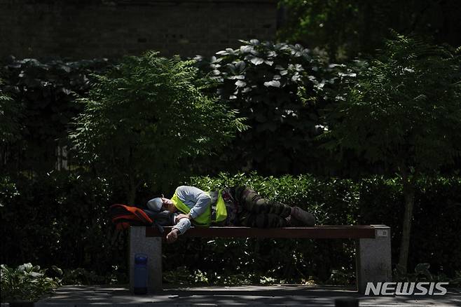 [베이징=AP/뉴시스] 26일 중국 베이징의 코로나19로 폐쇄된 공원에서 마스크로 눈을 가린 한 근로자가 벤치에 누워 낮잠을 자고 있다. 2022.05.26.