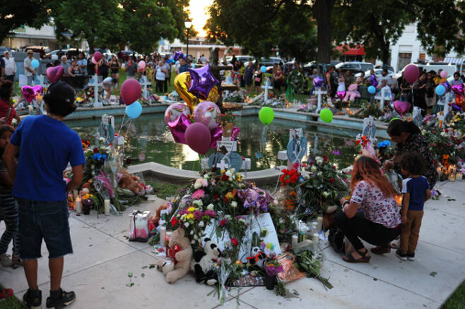 미국 텍사스주 초등학교 총기난사로 숨진 희생자를 기리는 추모공간에 27일(현지시간) 사람들이 모여 슬픔을 나누고 있다.   AFP연합뉴스