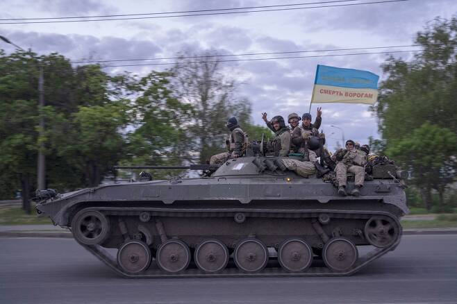 우크라이나 군인들이 16일(현지시간) 제2 도시인 동북부 하르키우(하리코프)주(州) 거리에서 장갑차를 타고 이동하며 국기를 흔들고 있다. /연합뉴스