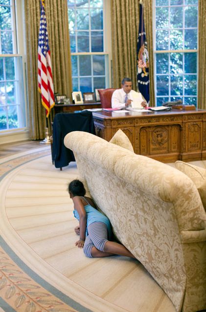 2009년 8월 버락 오바마 당시 대통령이 책상에 앉아 자료를 검토하고 있는 새, 막내딸 사샤(8)가 소파 뒤에 숨어 오바마를 놀래키려는 듯 보고 있다. /조선DB