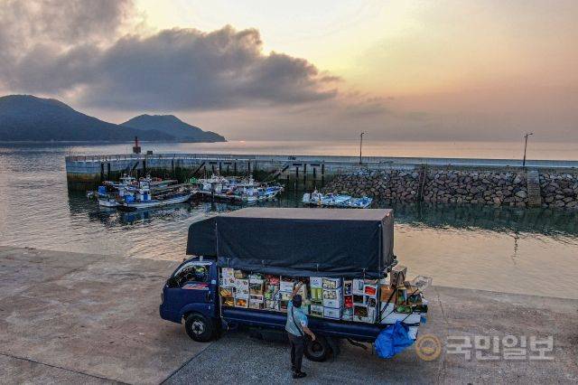 일을 마친 권씨가 노을을 배경으로 선착장에서 물건들을 정리하고 있다.