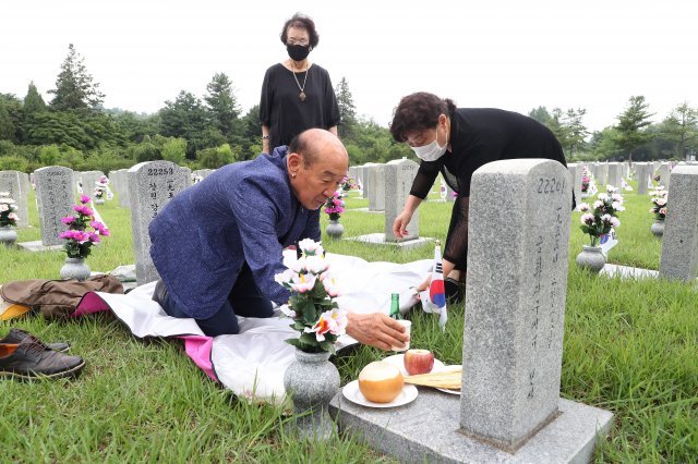 6.25 전쟁 발발 72주년을 하루 앞둔 24일 서울 동작구 국립서울현충원 6.25 전사자 묘역에서 유가족이 술잔을 올리고 있다.