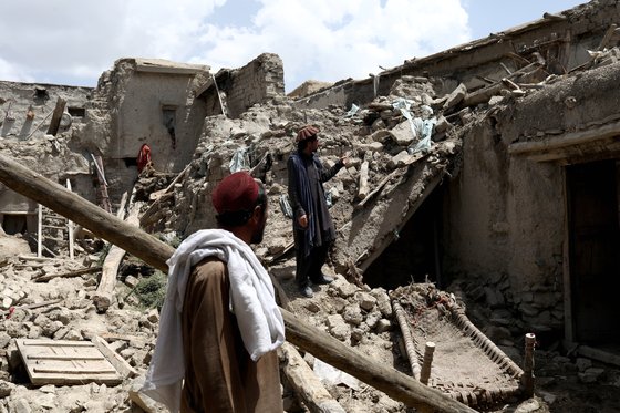 23일(현지시간) 지진으로 무너진 집 잔해 위에 서 있는 아프간 남성. [로이터 연합뉴스]
