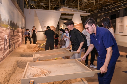방문객들이 대명궁 Archaeological Exploration Center에서 고고학 작업을 경험하고 있다.