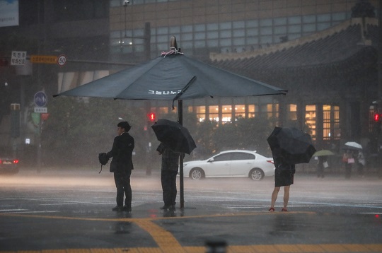 지난 23일 오후 서울 종로구 광화문광장 인근에서 쏟아지는 폭우에 시민들이 우산을 쓴 채 이동하고 있다. 사진=뉴시스