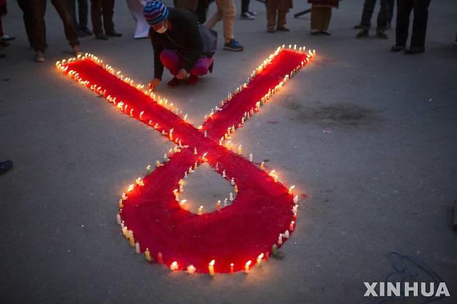 [카트만두=신화/뉴시스] 세계 에이즈의 날을 하루 앞둔 11월30일(현지시간) 네팔 카트만두에서 에이즈 인식 캠페인이 열려 한 자원봉사자가 촛불을 밝히고 있다. 2021.12.01.