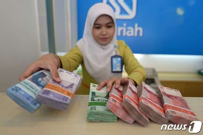 인도네시아 자카르타의 한 은행에서 직원이 루피아 지폐를 책상 위에 내놓고 있다. © AFP=뉴스1