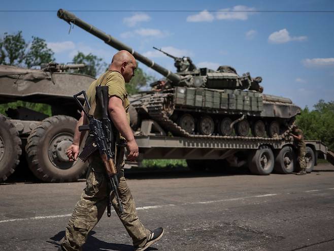 우크라이나 동부 도네츠크주의 도로에서 우크라이나군 병사가 탱크를 실은 트럭 옆으로 지나가고 있다.