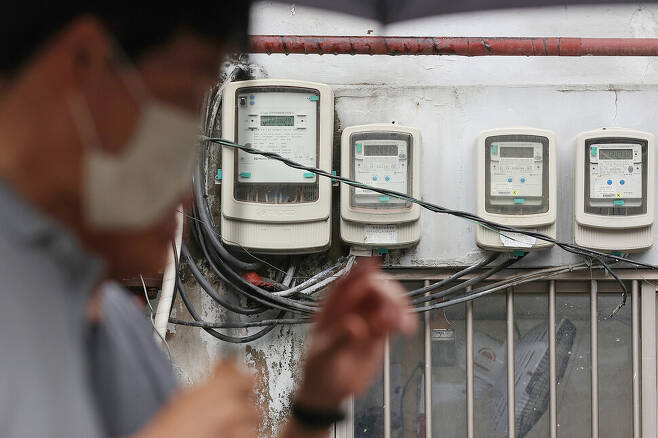 한국전력이 7월부터 전기요금을 킬로와트시(㎾h)당 5원 올린다고 발표한 27일 오후 서울 시내의 전기계량기 앞을 시민들이 지나가고 있다. 연합뉴스