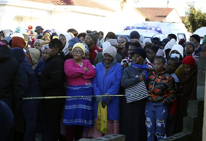지난 26일(현지시각) 남아프리카공화국 이스트런던의 한 나이트클럽 밖에서 인파가 모여 사망한 시신을 운구하는 모습을 지켜보고 있다. 이스트런던=AP연합