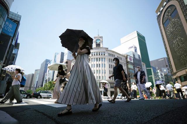 때 이른 폭염에 28일 도쿄 시민들이 양산을 쓰고 횡단보도를 건너고 있다. 일본 기상청에 따르면 도쿄의 최고기온이 6월에 사흘 연속 35도를 넘은 것은 관측 이래 처음이다. 도쿄=AP 연합뉴스