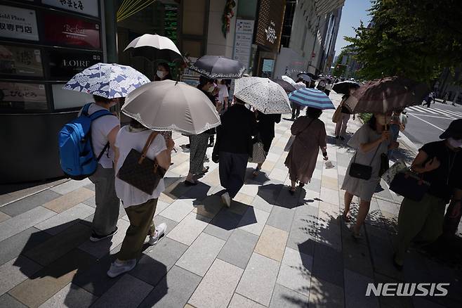 [도쿄=AP/뉴시스] 28일 일본 도쿄에서 강렬한 햇빛을 피하고자 양산 쓴 시민들이 건널목을 건너고 있다. 일본 기상청이 수십 년 만에 처음으로 장마가 짧게 지나갔다고 발표함에 따라 정부는 수도권이 불볕더위에 휩싸여 전력난이 우려된다며 에너지 절약을 당부했다. 2022.06.28