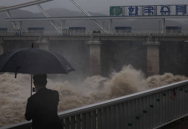 서울에 집중호우가 쏟아진 30일 경기 하남시 팔당댐 근처에서 한 시민이 집중호우로 방류 중인 댐을 보고 있다. |연합뉴스